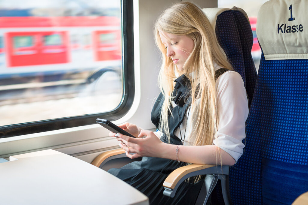 Une jeune fille assise dans le train avec une tablette