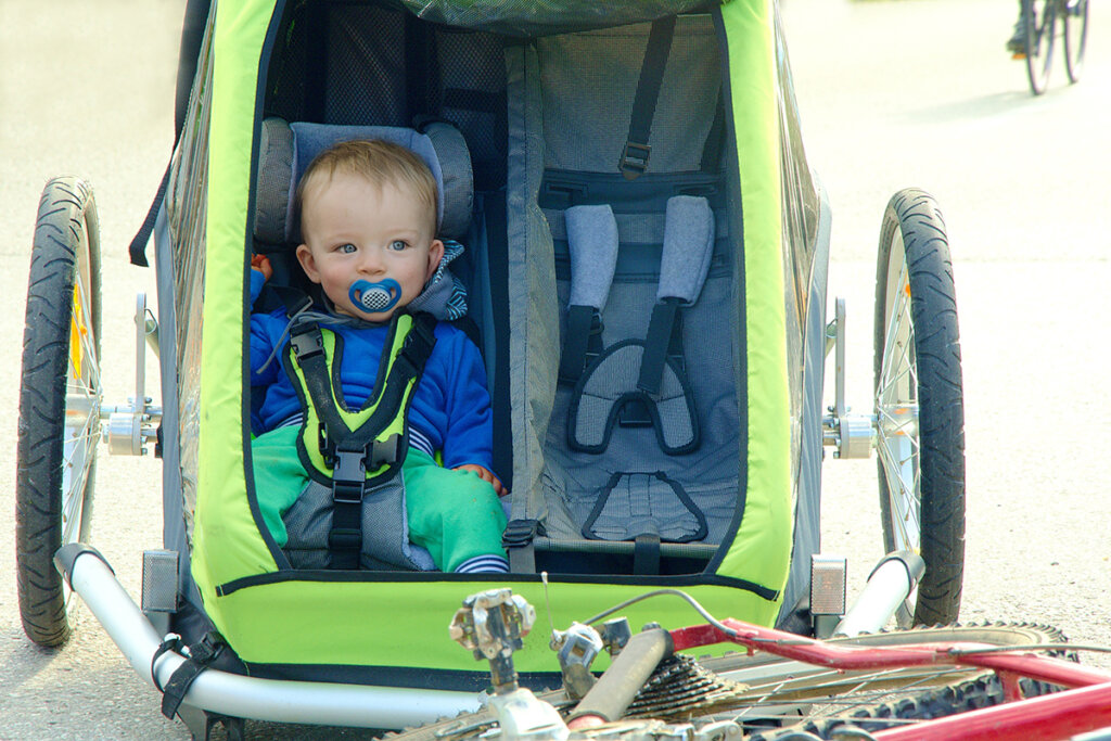 Petit enfant assis dans une remorque à vélo verte