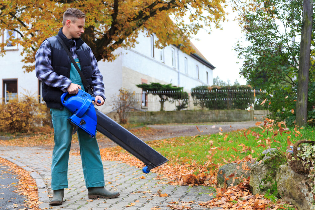 Homme soufflant sur un trottoir