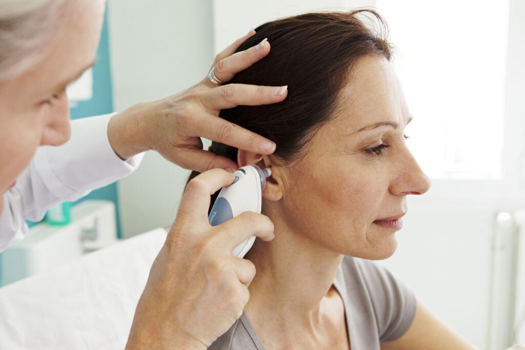 médecin prend la température d'une femme dans l'oreille