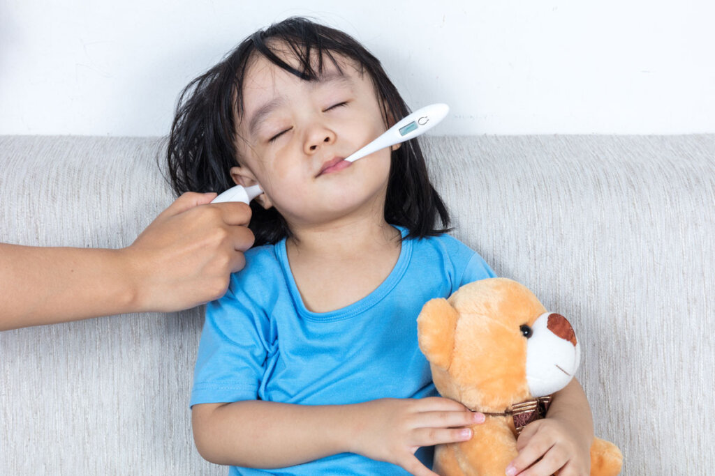 Enfant avec thermomètre médical dans l'oreille et la bouche