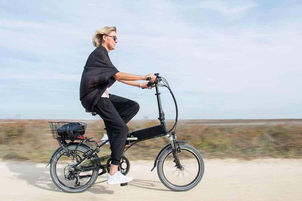 Femme sur un vélo pliant sur la plage