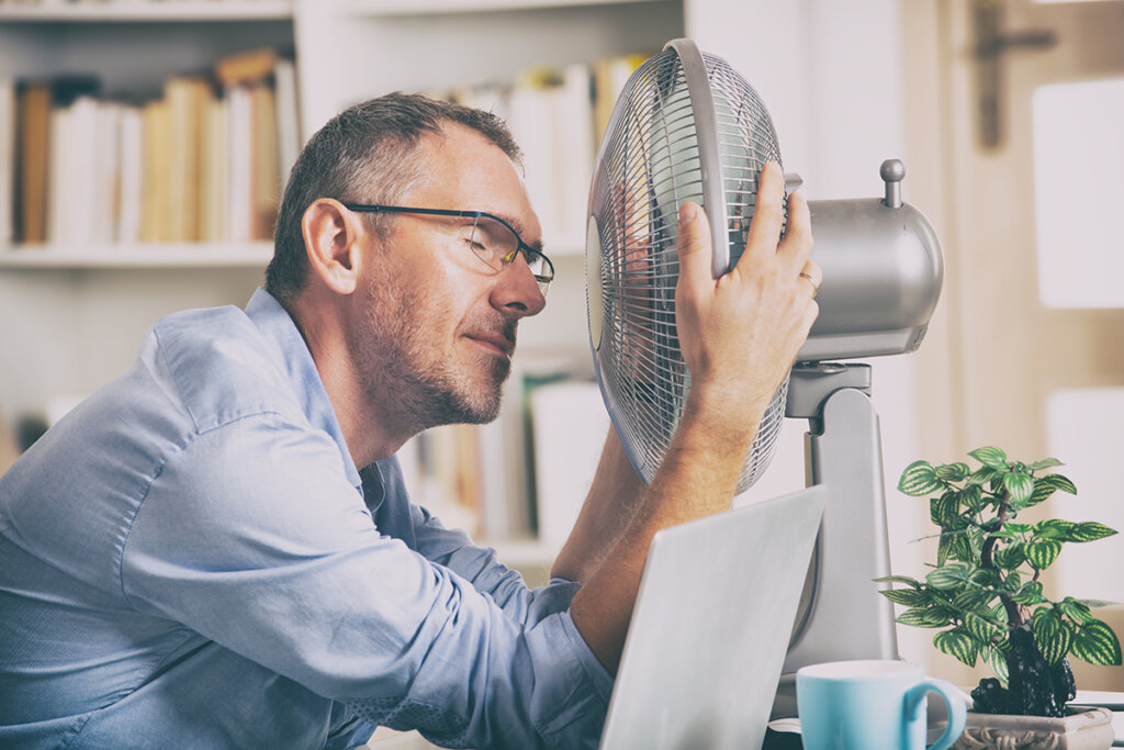 homme devant un ventilateur dans un bureau