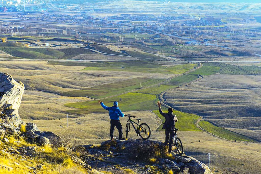 des cyclistes se tiennent sur une montagne et regardent le paysage en contrebas