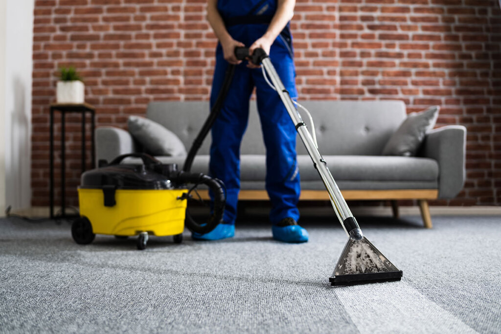 Un homme nettoie un tapis avec un aspirateur industriel