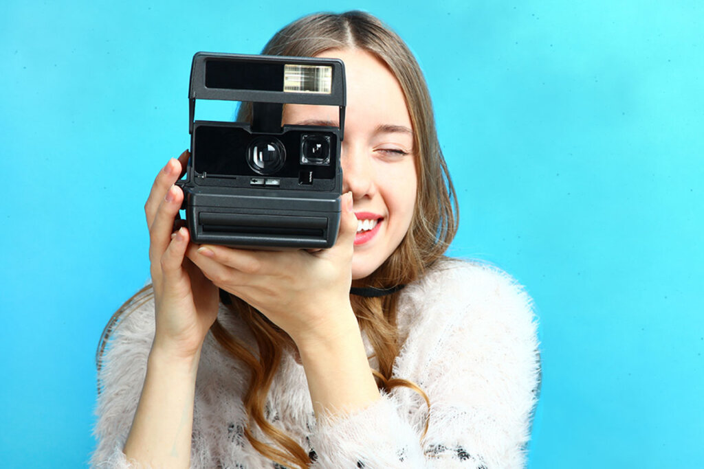 une femme prend une photo avec un appareil photo instantané