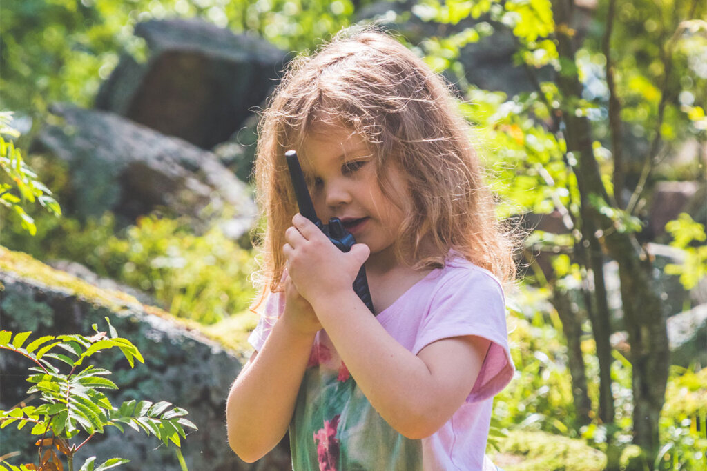 Une enfant parle dans un talkie-walkie en forêt