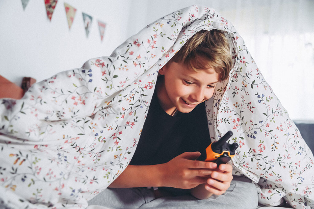 Un enfant joue avec un talkie-walkie au lit