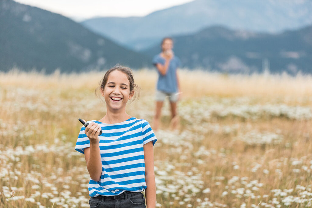 Deux frères et sœurs jouent avec des talkies-walkies en plein air.