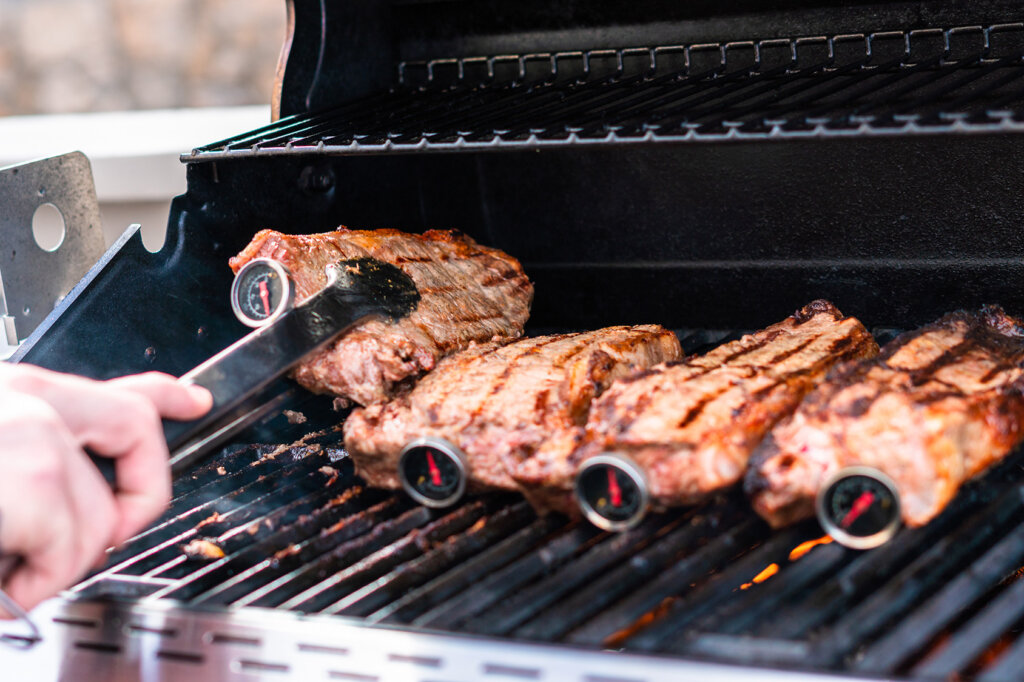 Quatre steaks avec thermomètre à barbecue