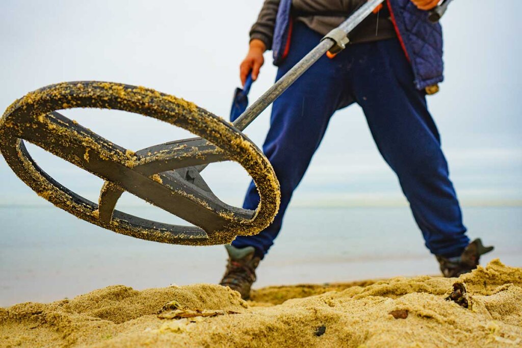 Homme debout dans le sable avec un détecteur de métaux