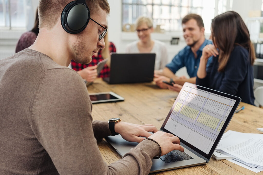 jeune homme assis devant son ordinateur portable avec un casque sur les oreilles