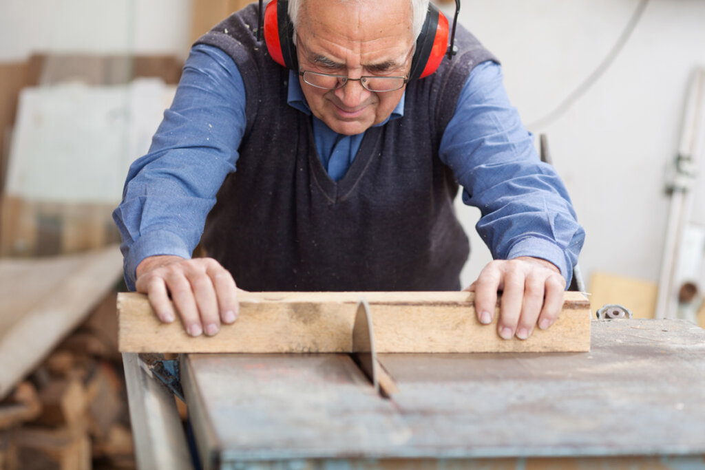 Un homme coupe du bois avec une scie circulaire à table