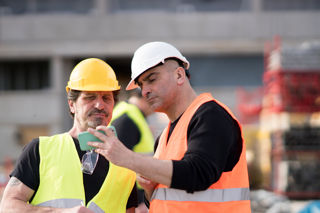 Un ouvrier du bâtiment utilise un smartphone sur un chantier