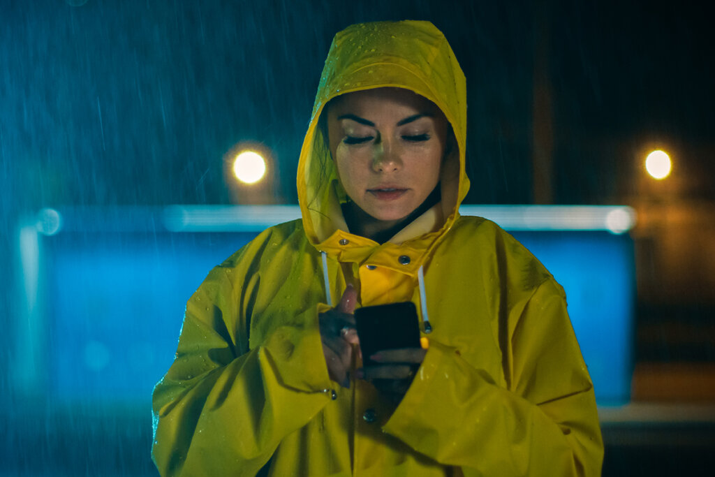 Une femme sous la pluie utilise un smartphone