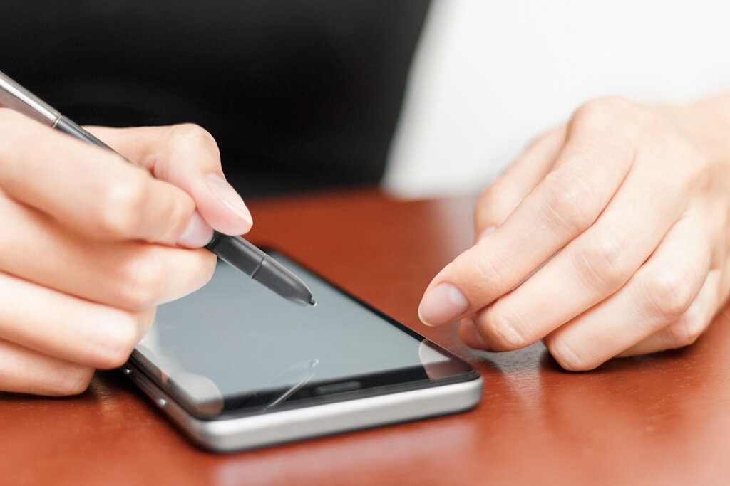 Une femme utilise un smartphone avec un stylo