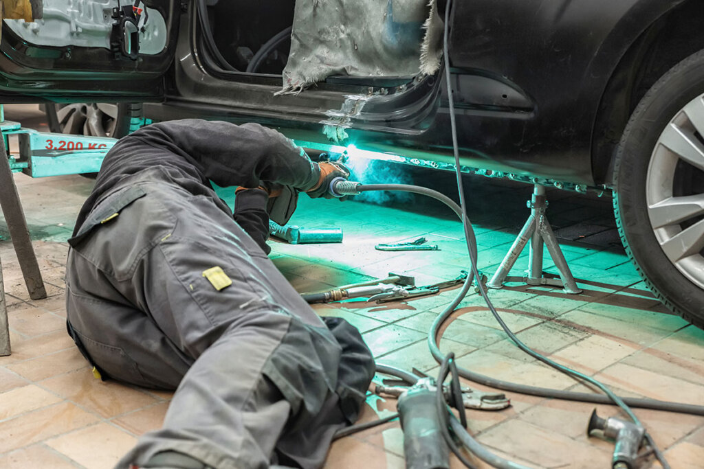 Personne en train de souder une voiture dans un atelier