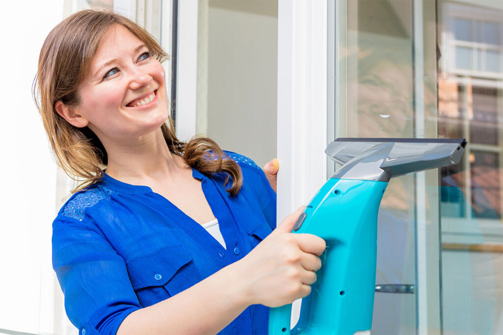 Une femme utilise un aspirateur à vitres